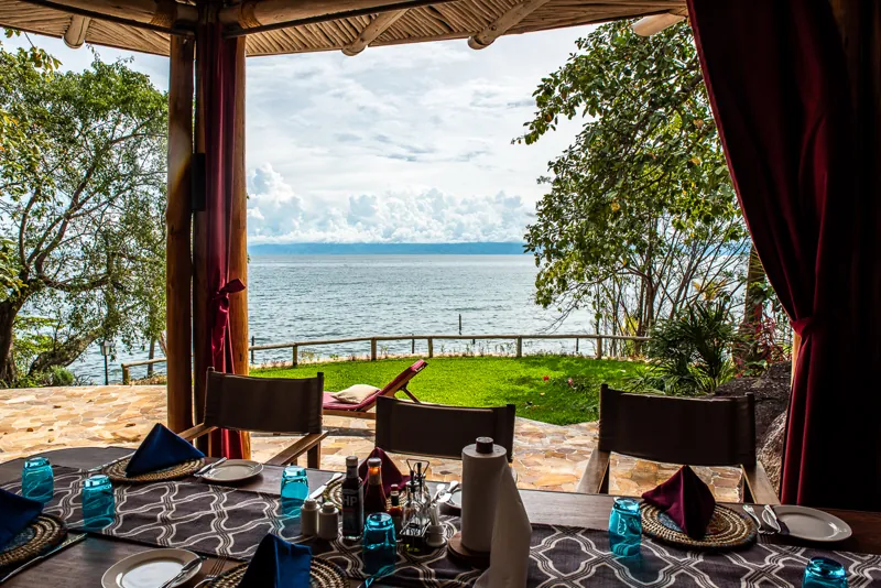 Une table dressée sous la paillote de bambou, avec vue sur la pelouse et le lac