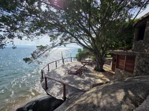 A timber deck built out over the rocks beneath a spreading tree, looking along the shore of Lake Tanganyika