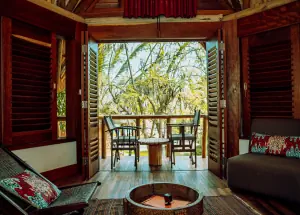 Une chambre, portes ouvertes sur le balcon et les arbres
