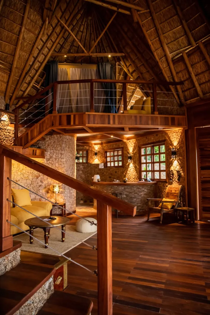 Un salon sous chaume en double hauteur, murs de pierre, sols en bois et chambre en mezzanine